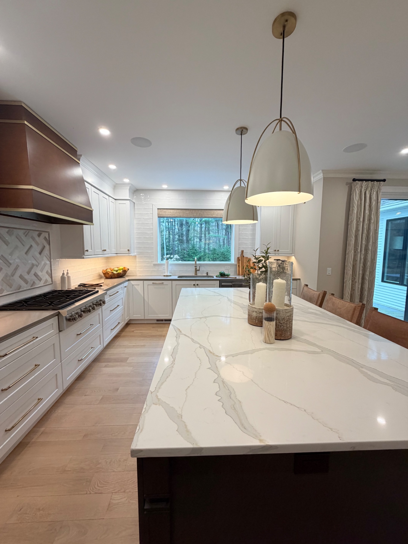 Pristine marble island kitchen with copper hood